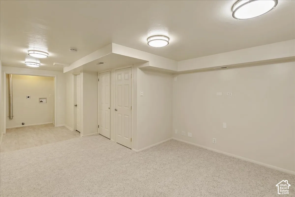 Neutral-toned carpeted flooring, multiple recessed light fixtures, and two six-panel closet doors
