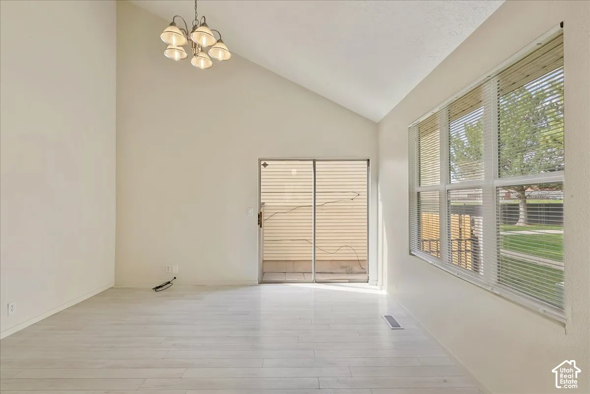 Vaulted ceilings, wood-finish flooring, multi-pane windows, and a multi-arm chandelier