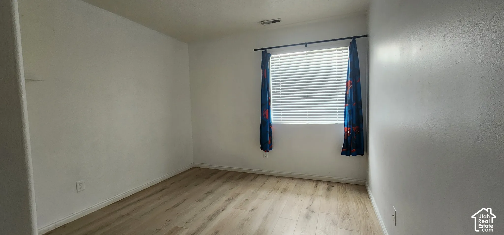 Room featuring wood-finish flooring and a single window with horizontal blinds