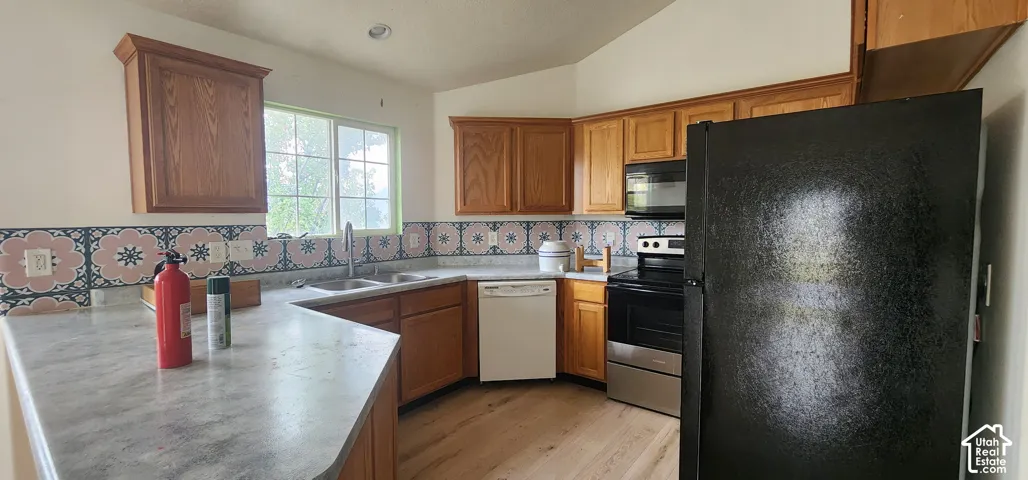 Kitchen featuring wood-finish cabinetry, patterned tile backsplash, wood-finish flooring, and a stone-finish countertop