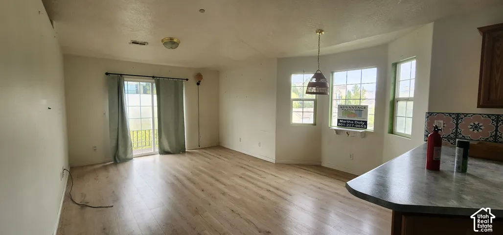 Open-concept space featuring wood-finish flooring, a bay window, a sliding glass door, and a pendant light fixture