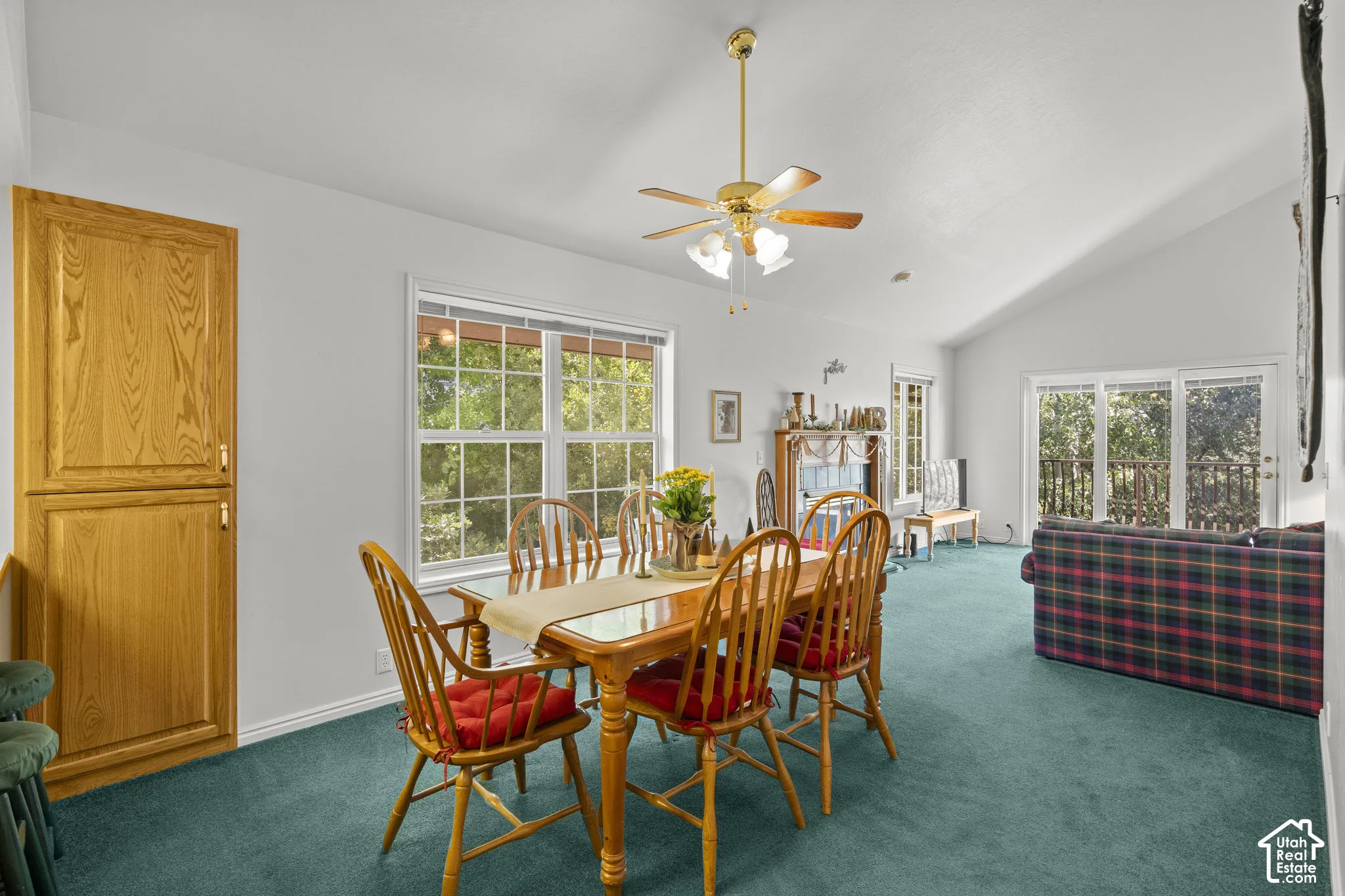 Vaulted ceiling with a central ceiling fan and light fixture, built-in floor-to-ceiling wooden cabinetry, multi-pane windows, and a sliding glass door