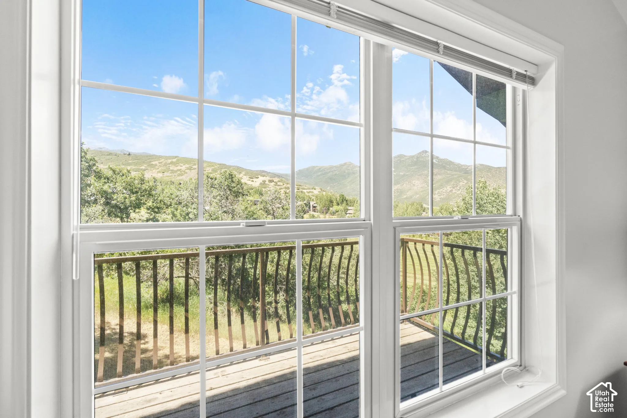 Dual-pane windows with white trim framing mountain scenery and an exterior deck with a metal railing