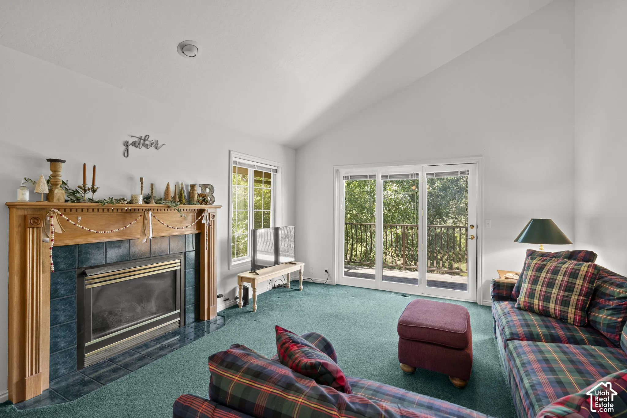 Vaulted ceilings, fireplace with wood mantel and tile surround, and glass sliding doors providing access to an exterior deck