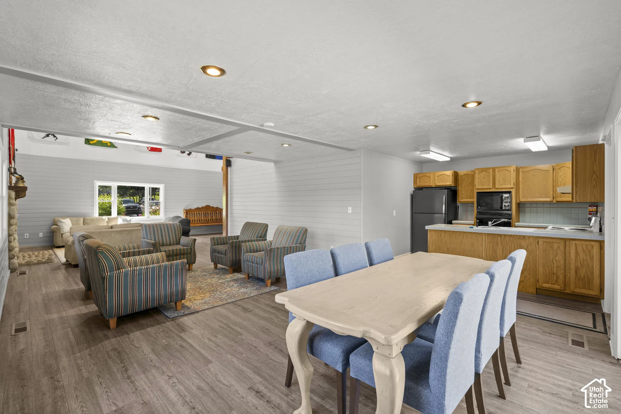 Open-concept interior featuring wood-finish flooring, recessed lighting, horizontal wall paneling, and wood cabinetry with a peninsula