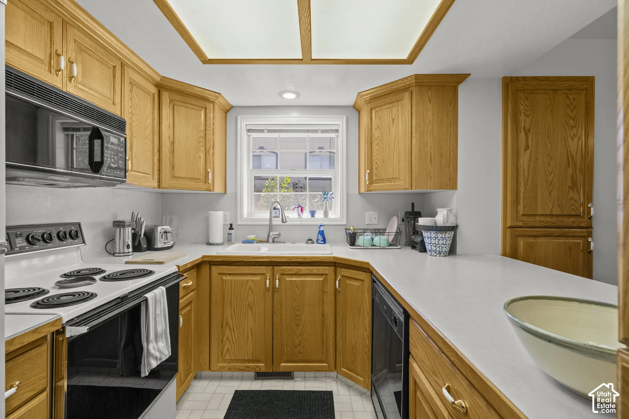 Kitchen featuring wood cabinetry, solid-surface countertops, integrated ceiling lighting, and a dual-basin sink with a gooseneck faucet