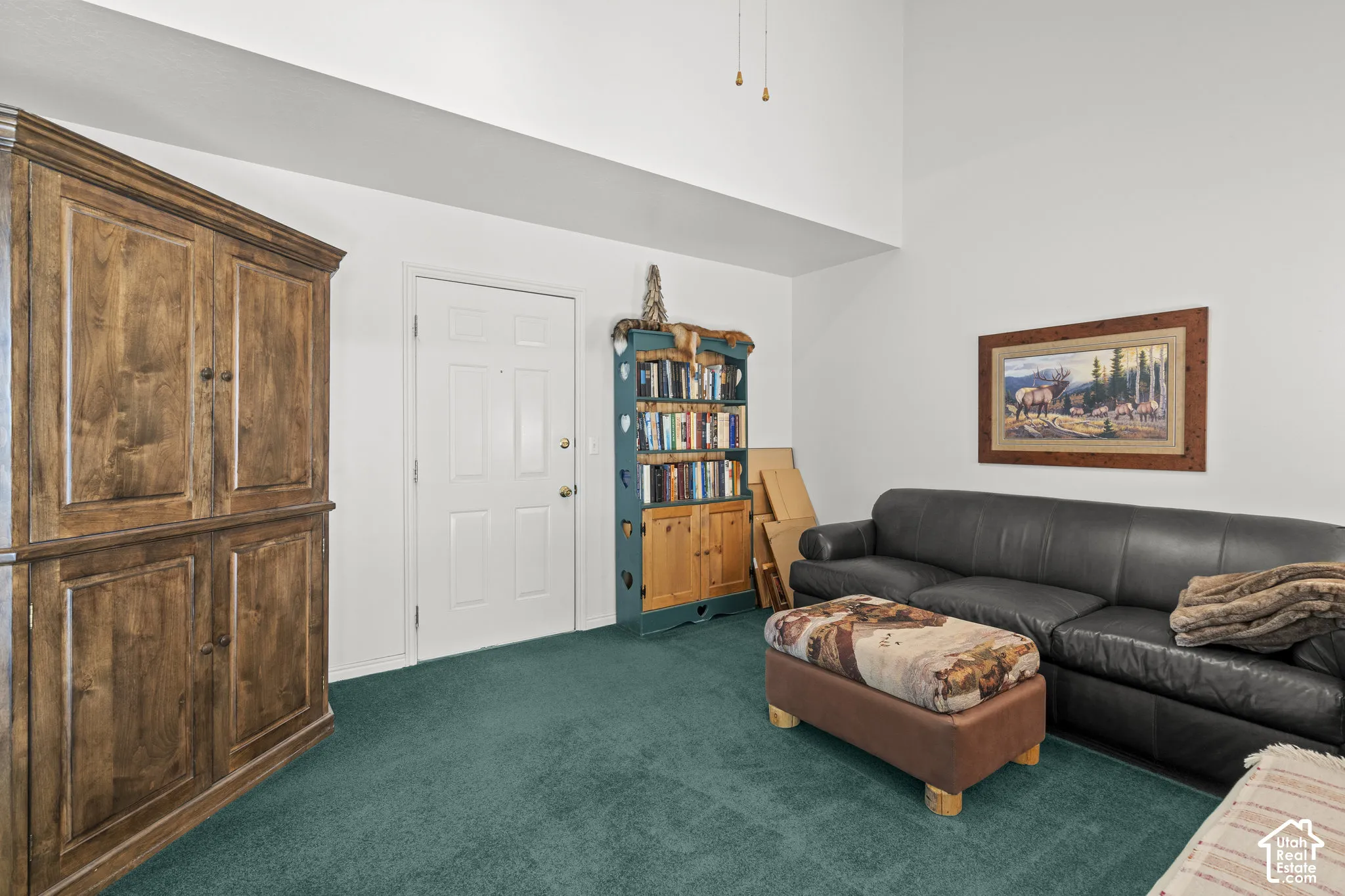 High-ceiling interior space featuring carpeted flooring and a solid-panel entry door