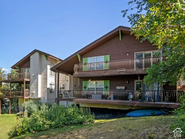 Multi-level exterior featuring horizontal wood siding, stucco accent walls, stacked wood-railing balconies, and expansive grounds