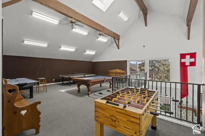 Vaulted ceiling featuring exposed wood-finish beams, recessed skylights, linear surface-mounted lighting, and iron balustrades