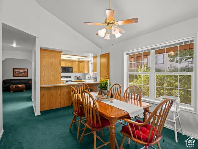 Dining area featuring vaulted ceilings, a ceiling fan with integrated lighting, and a large multi-pane window