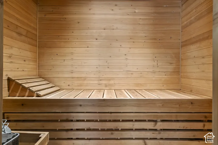 Sauna interior featuring natural wood wall paneling, built-in tiered wooden bench seating, and an integrated sloped wooden headrest