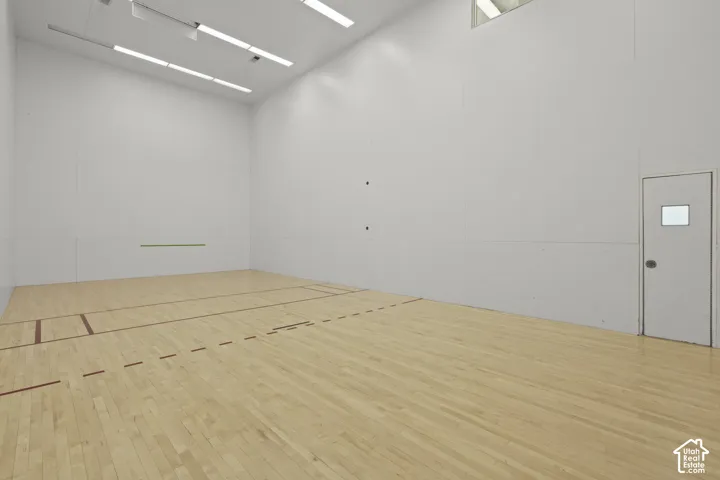 Recreational court featuring high-clearance ceilings, recessed linear lighting, smooth panel wall surfaces, and wood-finish flooring with marked court boundaries