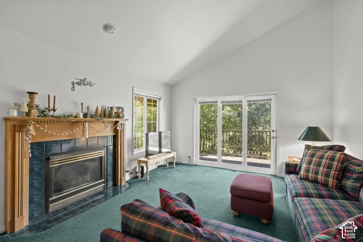 Vaulted ceilings, fireplace with wood mantel and tile surround, and glass sliding doors providing access to an exterior deck