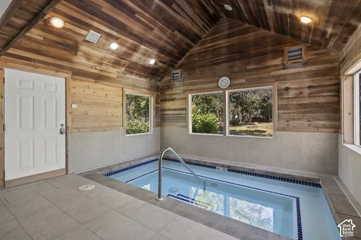 Indoor pool room featuring vaulted wood-plank ceilings, recessed lighting, tile surround flooring, and large windows