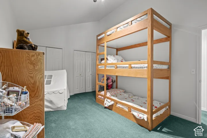 Room featuring vaulted ceilings, carpeting, and dual bi-fold door closets