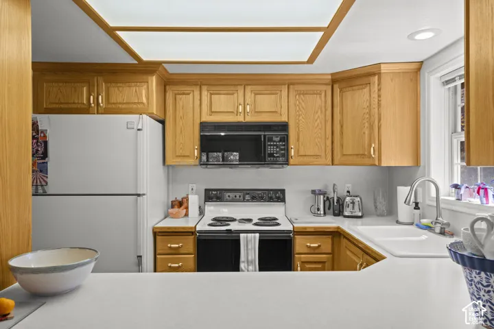Kitchen featuring wood cabinetry, integrated lighting, solid-surface countertops, built-in microwave, and white dual-basin sink