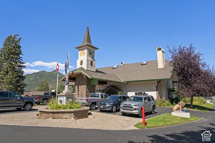 Exterior featuring a multi-story clock tower, stone masonry facade, asphalt shingle roofing, multiple skylights, and a decorative circular fountain