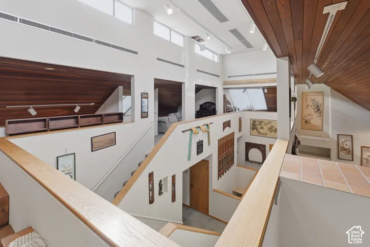 Vaulted ceilings with exposed wood-plank paneling, clerestory windows, natural wood stair railings, and track lighting