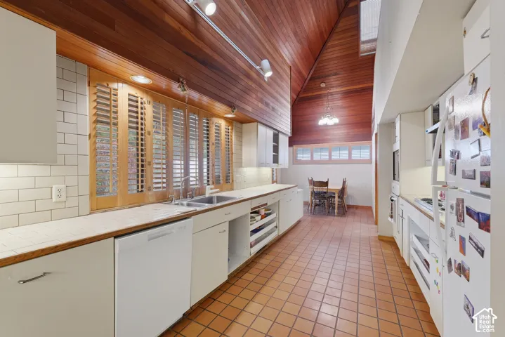 Kitchen featuring a vaulted wood-plank ceiling, terra-cotta tile flooring, white subway tile backsplash, and custom wood-slat window shutters
