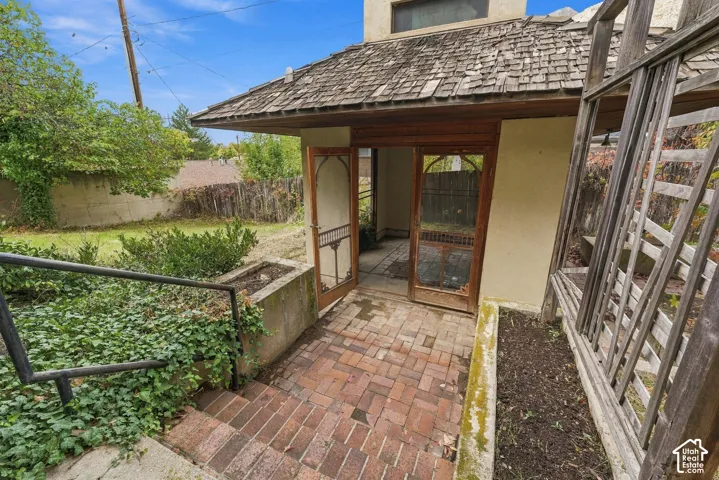 Exterior structure featuring a shake roof, brick-paved patio, wooden lattice trellis, and integrated concrete planters