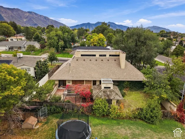 Expansive backyard featuring a brick patio, wooden pergola, detached gazebo, and mountain backdrop