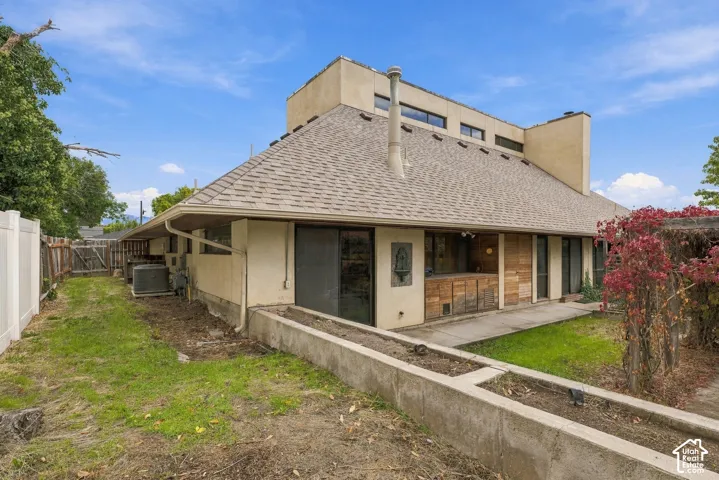 Exterior featuring a multi-level stucco facade, asphalt shingle roofing, sliding glass doors, concrete retaining walls, and wood-paneled siding accents