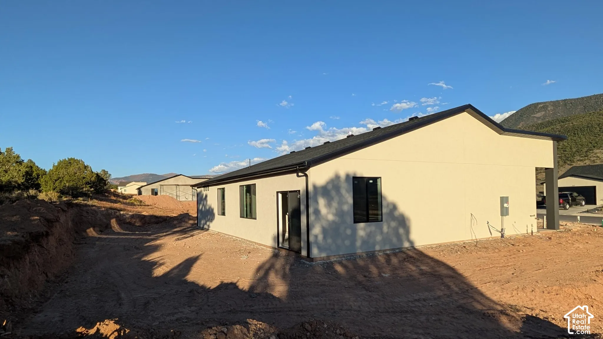 Stucco exterior featuring dark-framed windows, a pitched roof, and mountain backdrop
