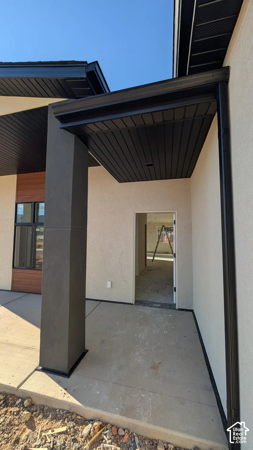 Covered entryway featuring smooth stucco exterior, dark metal soffit detailing, and a prominent structural column