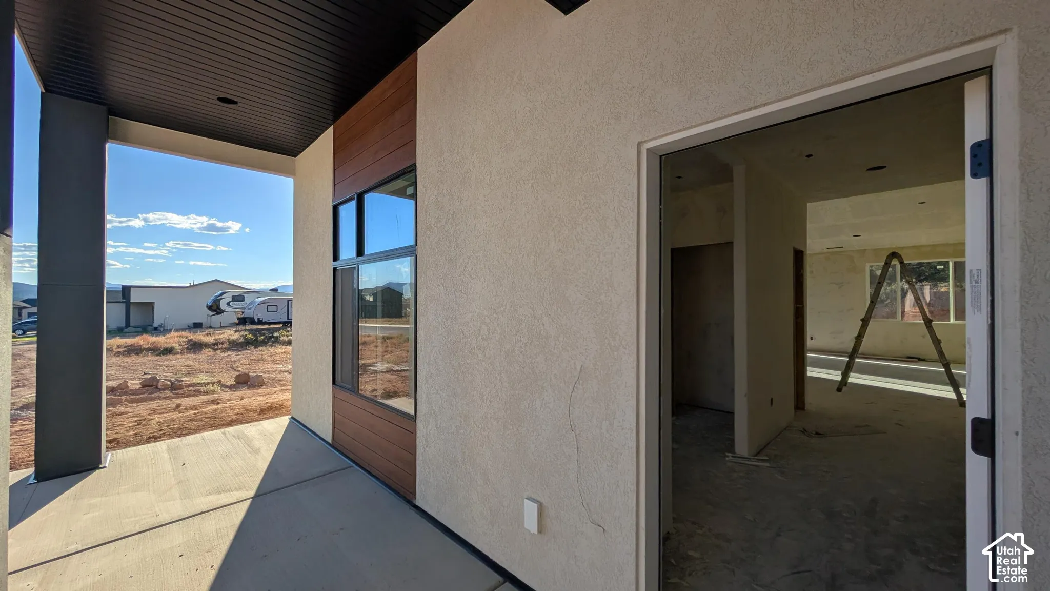Covered porch featuring concrete flooring, a smooth stucco facade, horizontal wood-finish siding, and a dark-toned ceiling soffit