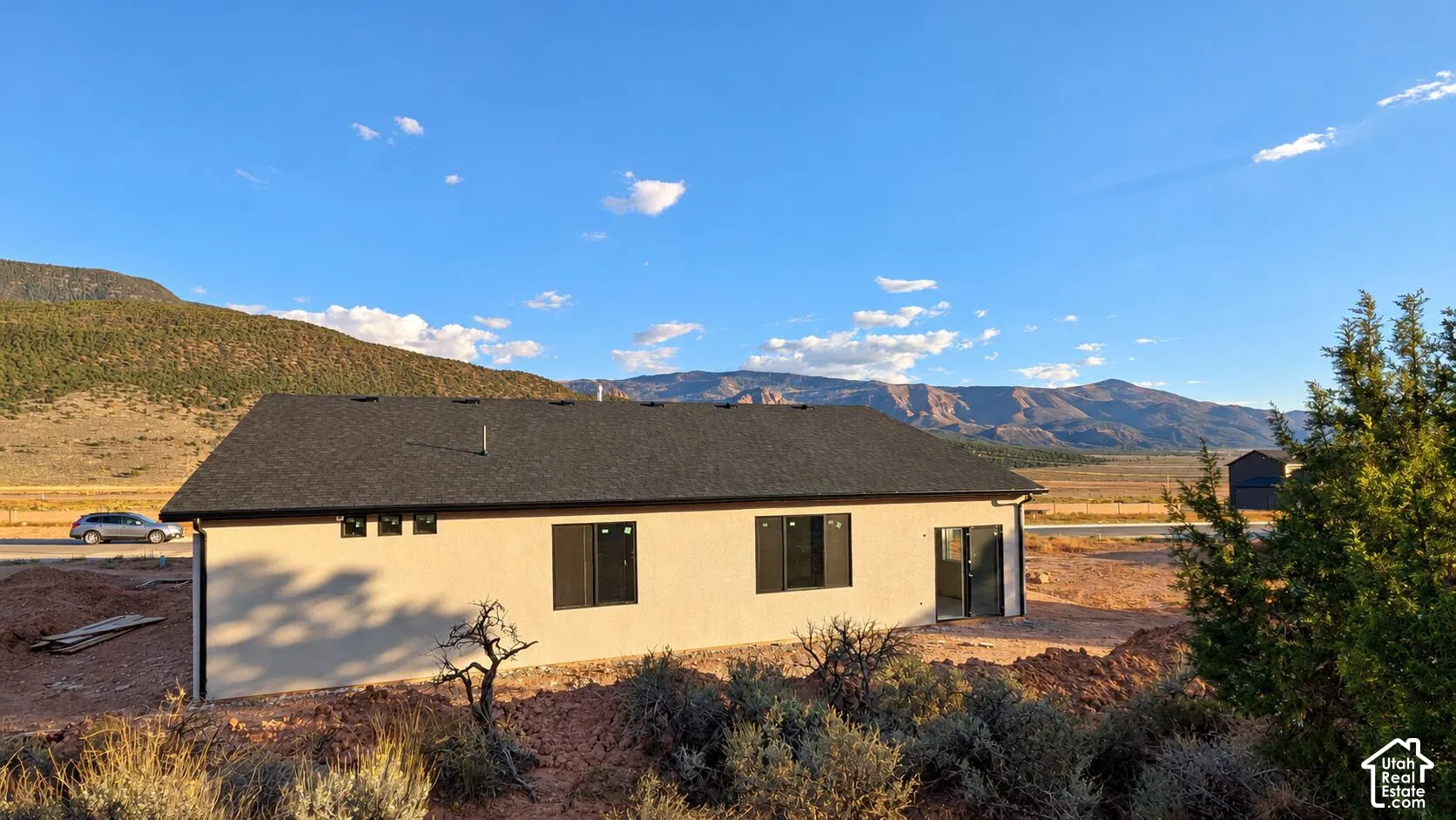Stucco exterior, asphalt shingle roof, and mountain backdrop