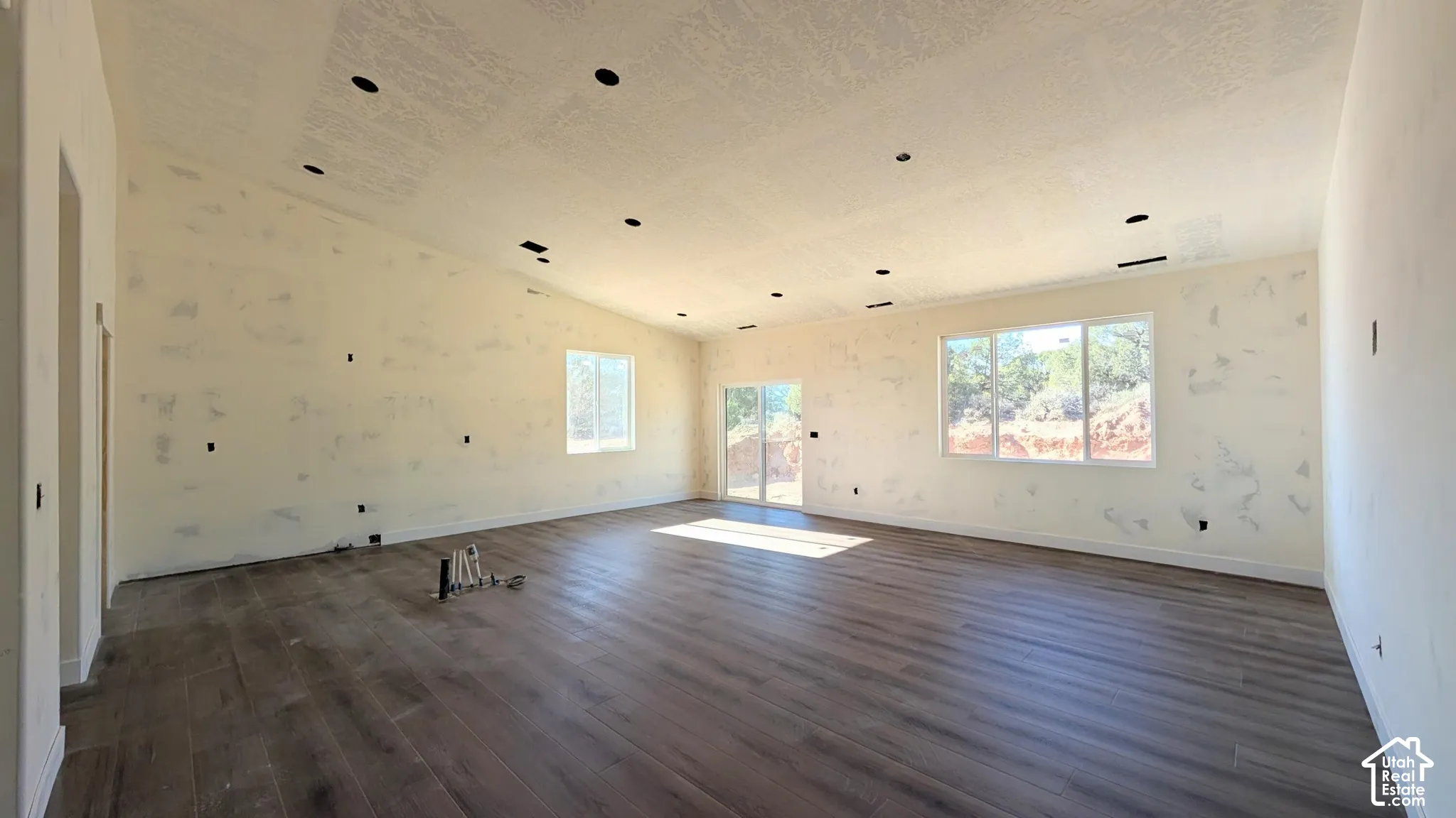 Open-concept interior featuring vaulted ceilings, recessed lighting, wood-finish flooring, and expansive windows