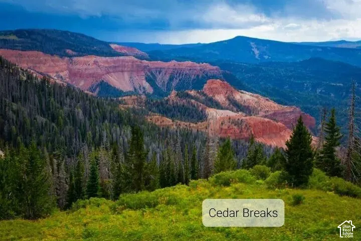 Cedar Breaks National Monument. Expansive landscape featuring dense evergreen forest, natural red rock formations, and mountain topography