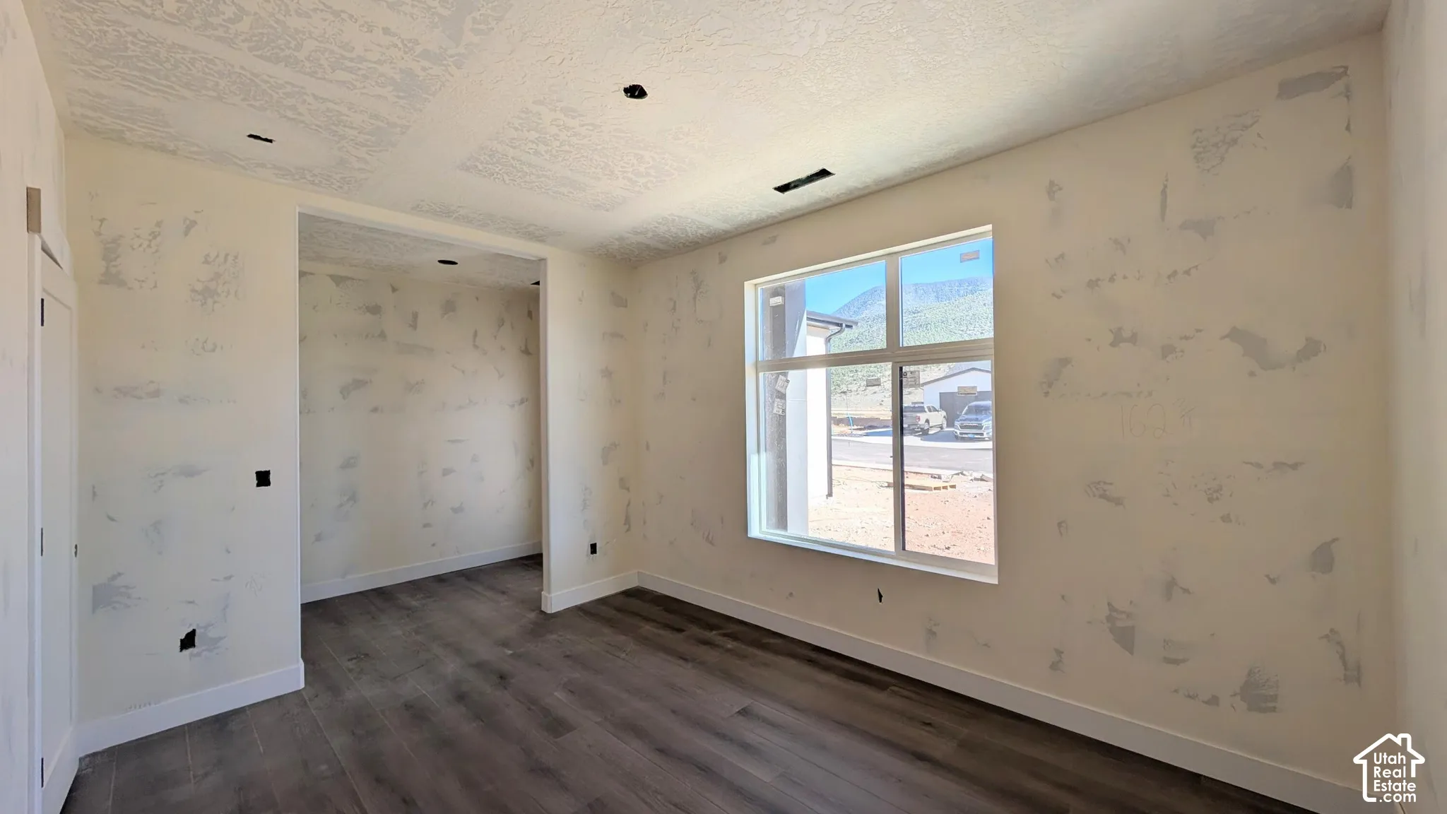 Interior space featuring wood-finish flooring, a large picture window with mountain backdrop, recessed ceiling lighting, and a textured wall finish