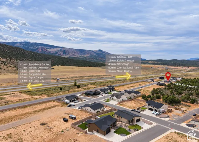 Aerial perspective of a residential neighborhood featuring mountain topography, desert landscaping, and paved roadway infrastructure