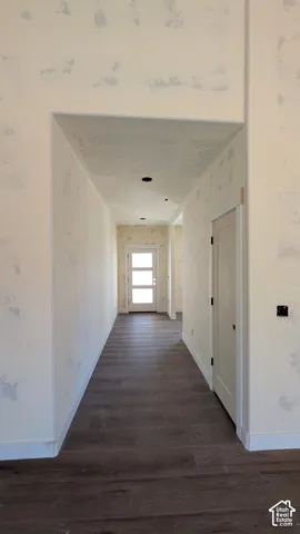 Hallway featuring wood-finish flooring, a solid-core door with matte black hardware, and an exterior door with triple-pane glass inserts