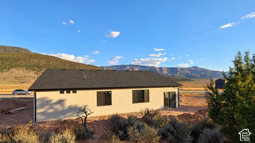 Stucco exterior, asphalt shingle roof, and mountain backdrop