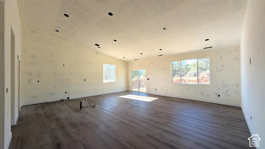Open-concept interior featuring vaulted ceilings, recessed lighting, wood-finish flooring, and expansive windows