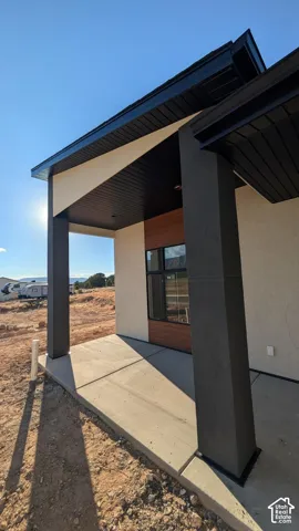 Modern covered patio featuring a concrete slab, high-contrast dark structural columns, a wood-finished accent wall, and black window framing