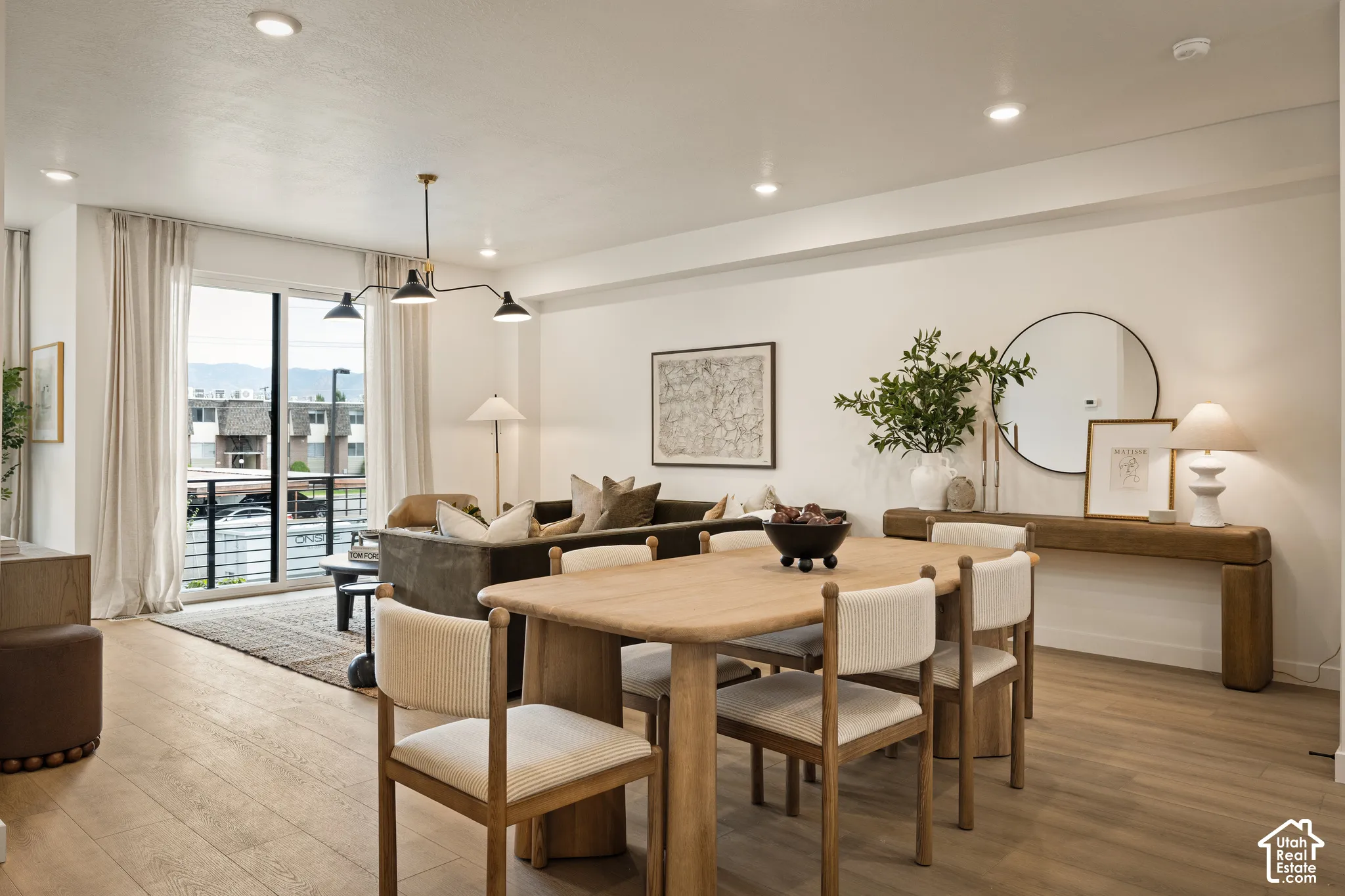 Open-concept interior featuring light wood-finish flooring, recessed lighting, and a modern multi-arm chandelier