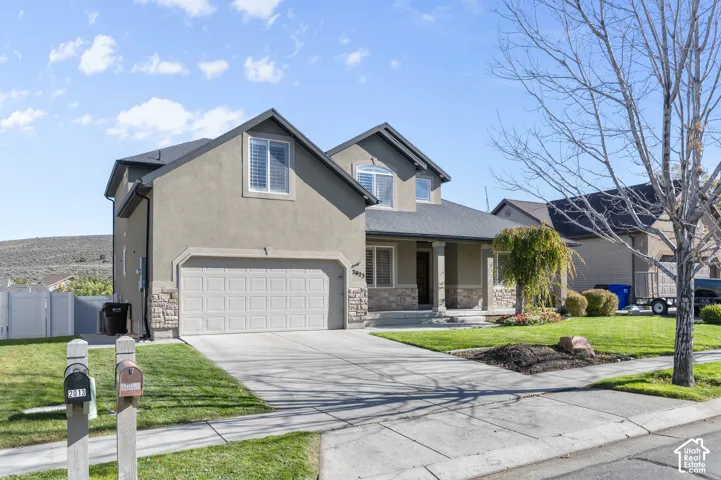 Stucco exterior featuring stone veneer accents, a concrete driveway, a covered front porch, and an attached two-car garage