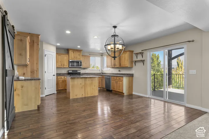 Kitchen featuring wood-finish cabinetry, stone-texture countertops, wood-finish flooring, a spherical multi-light chandelier, and sliding glass doors