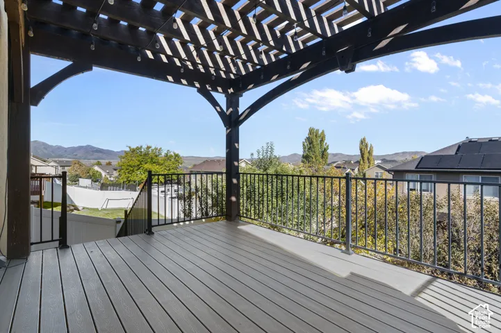 Raised deck featuring composite decking, a dark-finished wood pergola, and metal railings, set against a mountain backdrop