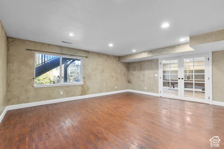 Interior space featuring wood-finish flooring, textured wall finishes, recessed lighting, and white-framed French doors