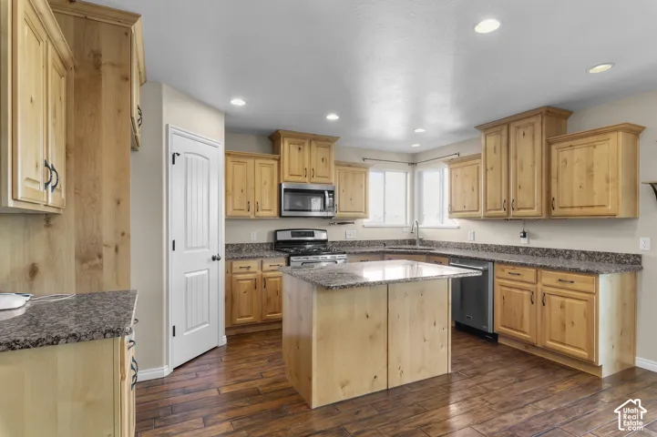 Kitchen featuring light wood cabinetry, stone-finish countertops, an island, recessed lighting, and wood-finish flooring
