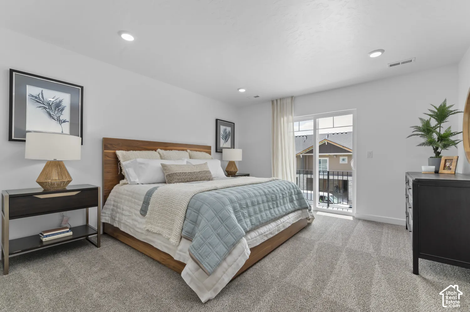 Neutral wall-to-wall carpeting, recessed ceiling lighting, and sliding glass door with access to a railed balcony