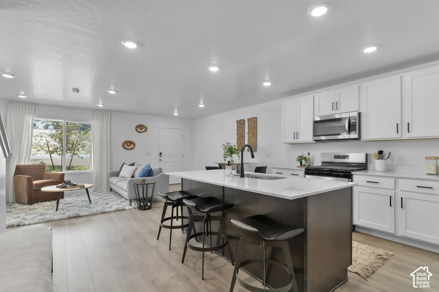 Kitchen featuring white cabinetry, quartz countertops, a central island with dark finish cabinetry, recessed lighting, and wood-finish flooring