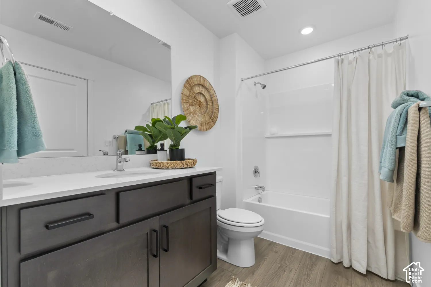 Bathroom featuring a dark wood-finish vanity with a white countertop, an undermount sink, a large wall-mounted mirror, and a tub-shower combination with a surround