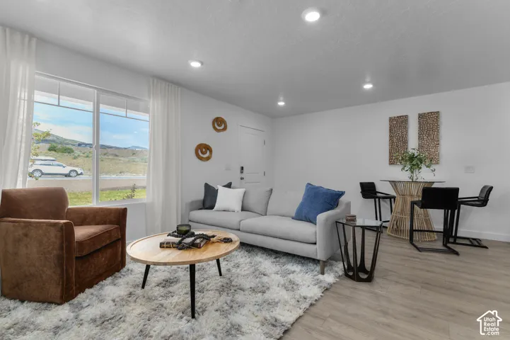 Open-concept space featuring wood-finish flooring, recessed lighting, and a large window with natural light