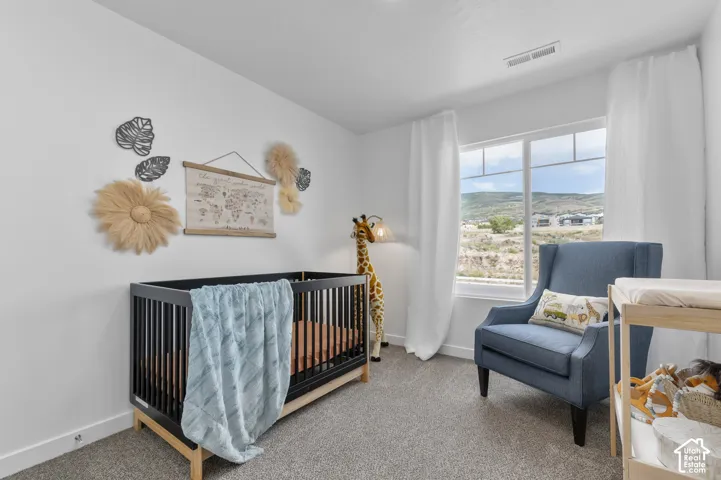 Room featuring neutral wall tones, carpeted flooring, and a large window showcasing mountain terrain