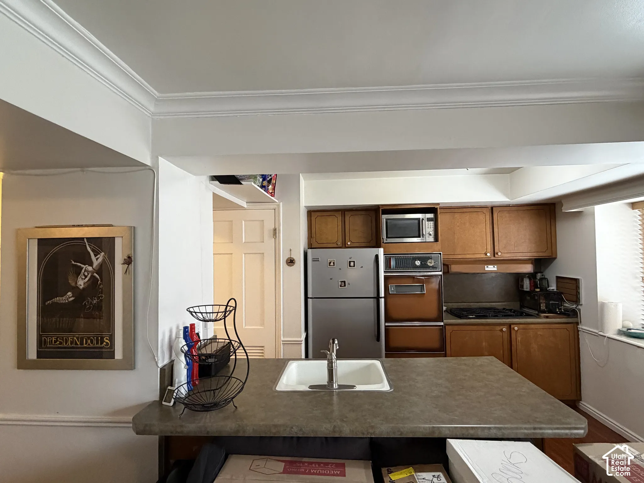 Kitchen featuring wood cabinetry, wall oven, microwave.  gas cooktop, and peninsula with an undermount sink and hard countertop